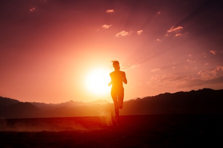 Lady running in the desert at sunsetの写真素材