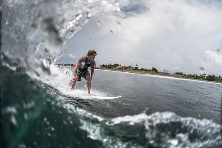INDONESIA, BALI, CANGGU - NOVEMBER 30 2016: Young surfer riding on the wave in the ocean