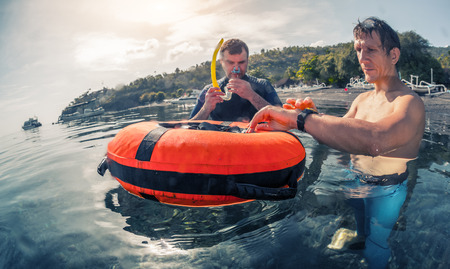 Freedivers training static breath hold in shallow water of a calm bay. Coach watching student