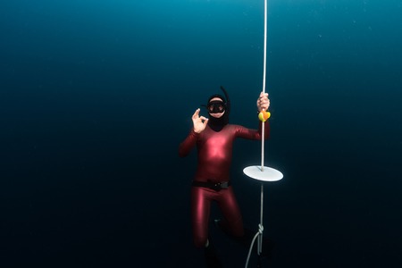 Free divers showing OK sign hanging on a depth by the end of training lineの写真素材