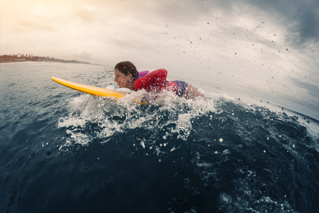 Young lady surfer trying to catch the wave in the oceanの写真素材