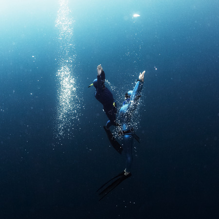 Two free divers ascending from the depth close to each other with lots of bubblesの写真素材