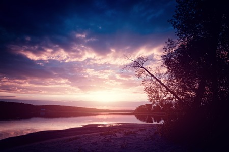Calm lake with autumn trees on the coast at sunsetの写真素材