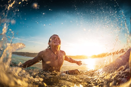 Happy surfer sits on board in the oceanの写真素材