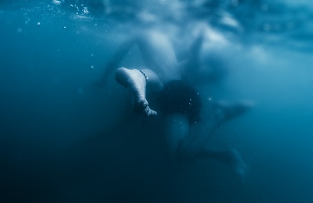 Couple plays underwater. Performs contact imrovisation dance in the waterの写真素材