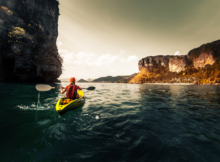 Woman paddles kayak in the calm sea among the tropical islandsの写真素材