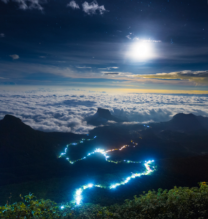 Illuminated path to the top of the mountain of Adams Peak with moon and stars in the sky. View from Adams Peak, Sri Lankaの写真素材