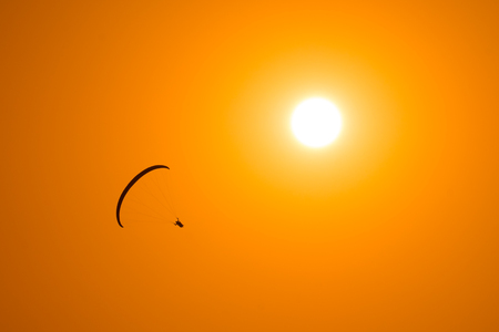 Paraglider flies in the sky with sun on the backgroundの写真素材