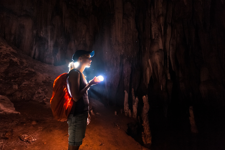 Young woman explores the cave with a torchの写真素材