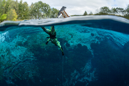 Split shot of a man diving in a blue crystal clear lake