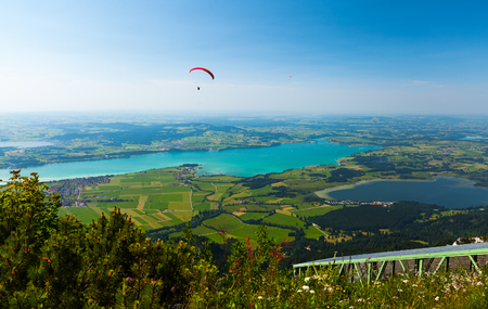 Paraglider flies over the green valley with lakes and towns. Area of the city of Fussen, Germanyの写真素材