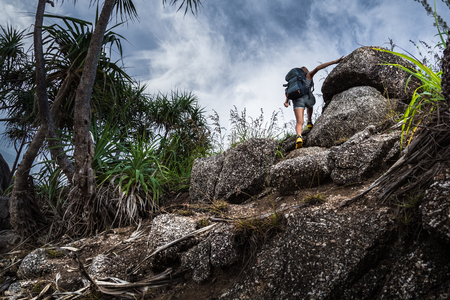 Woman hiker with backpack climbs steep rocky terrainの写真素材