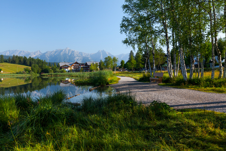 Walking way with green grass and trees on a coast of Alpine lake Seefeld, Austriaの写真素材