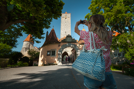 Young woman tourist walking in an old town of Rothenburg and taking a picture. Germanyの写真素材