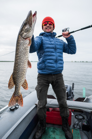 Happy angler holds big pike fishの写真素材