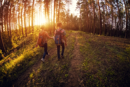 Two ladies walking on a road in a forest at sunny dayの写真素材