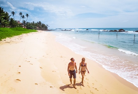 Couple walks along the tropical sandy beach at sunny day. Honeymoon and family vacation conceptの写真素材