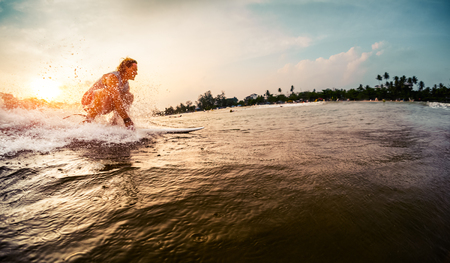 Surfer rides the wave during sunsetの写真素材