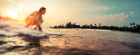 Surfer rides the wave during sunsetの写真素材