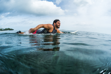 Muscular surfer with beard paddling in the oceanの写真素材