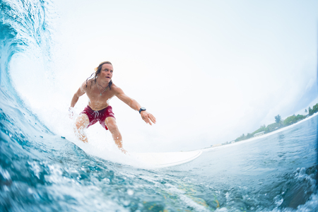 Young surfer rides the perfect tropical ocean wave. Extreme sport and active lifestyle concept. Surfspot named Jailbreak, Maldivesの写真素材