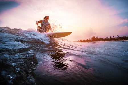 Surfer rides the ocean wave during sunset. Extreme sport and active lifestyle conceptの写真素材