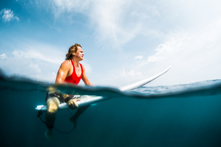 Surfer waits wave in an ocean, split shot with underwater viewの写真素材