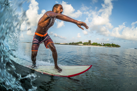 Asian professional surfer rides the ocean wave on a short board. Extreme sport and active lifestyle conceptの写真素材