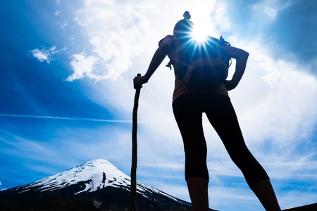 Woman hiker stands and enjoys volcano viewの写真素材