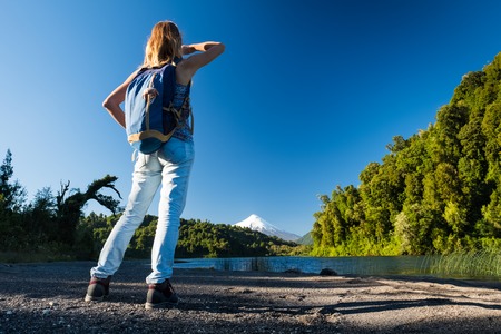 Woman hiker enjoys volcano view from the coast of a lakeの写真素材