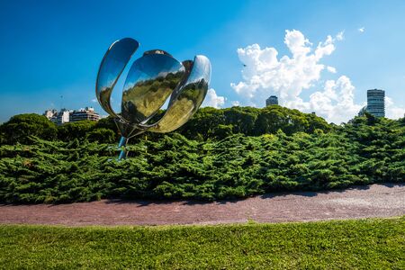 BUENOS AIRES - DECEMBER 22, 2017. Sculpture Floralis Generica surrounded by greenery on sunny day with some buildings of the city on the background.のeditorial素材