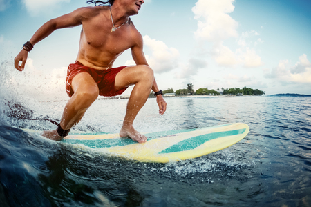Young man surfer rides the ocean tropical wave during sunrise surf sessionの写真素材