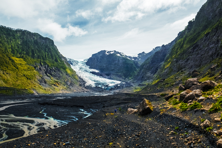 Hiker walks on the valley between mountains and with a glacier melting on the background. Pumalin National Park, town of Chaiten, Chileの写真素材