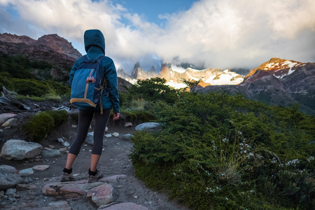 Hiker stands on the trail and enjoys mountains covered in cloudsの写真素材