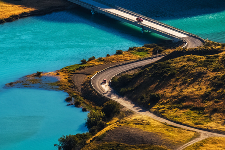 Two cars crossing blue river on the bridge. Chileの写真素材