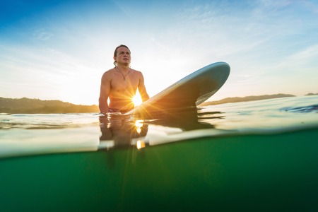 Young surfer waits a wave on line up at sunriseの写真素材