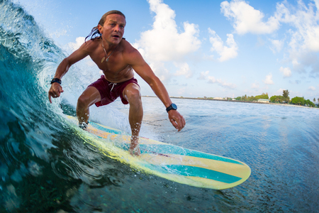 Young amateur surfer rides ocean wave in Maldivesの写真素材