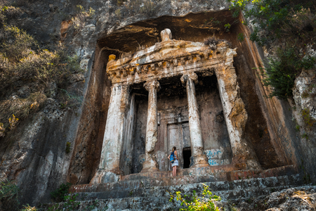 Amyntas rock tombs - 4th BC tombs carved in steep cliff. Tourist stands in front of the door. City of Fethiye, Turkey.の写真素材