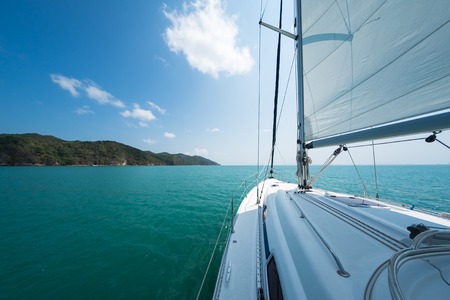 Sailing boat moves in a sea with troical island on the horizon. Thailandの写真素材
