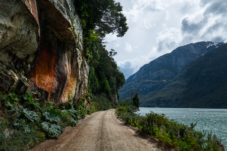 Gravel Patagonian road between lake and mountain. Road located in place named Valle Exploradores  in Chileの写真素材
