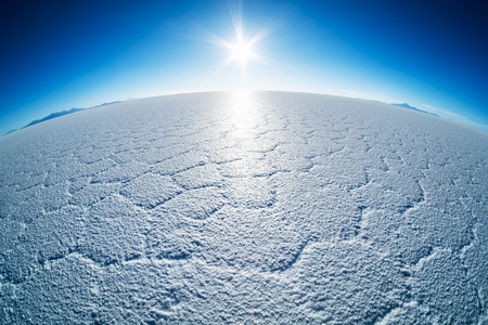 Salar de Uyuni salt flat with salt patterns and sun close to the horizon, Boliviaの写真素材
