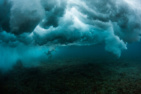 Underwater view of the surfer trying to pass powerful ocean waveの写真素材