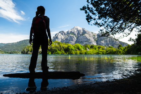 Silhouette of the lady hiker standing on the coast of a lake. Argentinaの写真素材