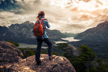 Tourist hiker with red backpack takes pictures of the valley with mountains and lakes. Patagonia, Argentinaの写真素材