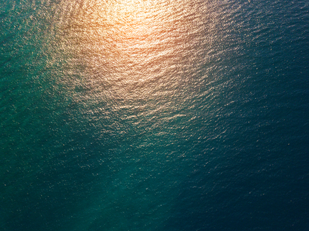 Sea surface aerial view with yellow sun reflectionの写真素材