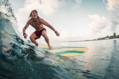Young surfer rides ocean tropical waveの写真素材