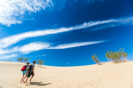 Couple of hikers walks barefoot on the sandy desertの写真素材