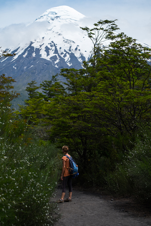 Woman hiker stands on the path in a park with snow capped volcano of Osorno on the backgound. Chileの写真素材