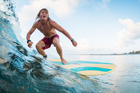 Young surfer rides ocean tropical waveの写真素材