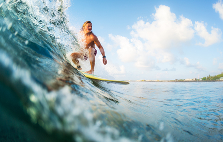 Young surfer rides ocean tropical waveの写真素材
